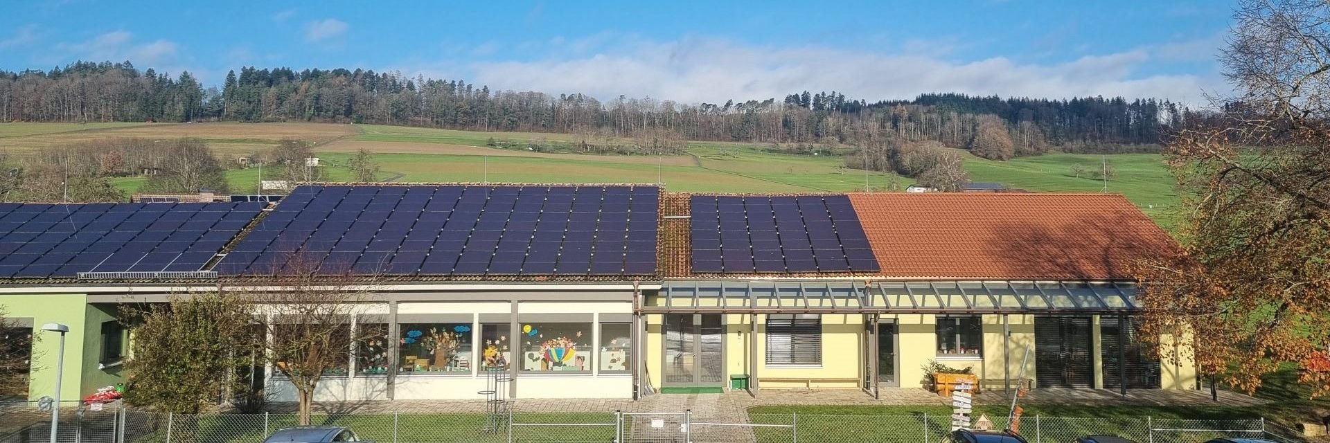 Solarpanel-bedecktes Kindergartengebäude in einer idyllischen Landschaft.